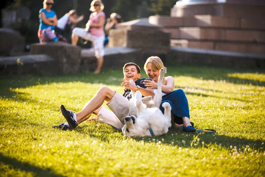 Happy couple playing with dog in clean backyard maintained by professional pooper scooper service